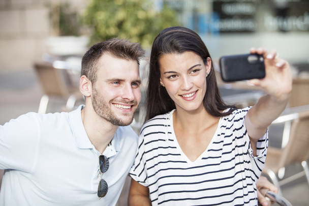 Happy couple taking a selfie photo with a smart phone in a restaurant terrace - Fotografie, Obrázek