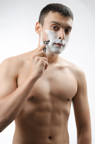 young man shaving with a razor - Foto, afbeelding