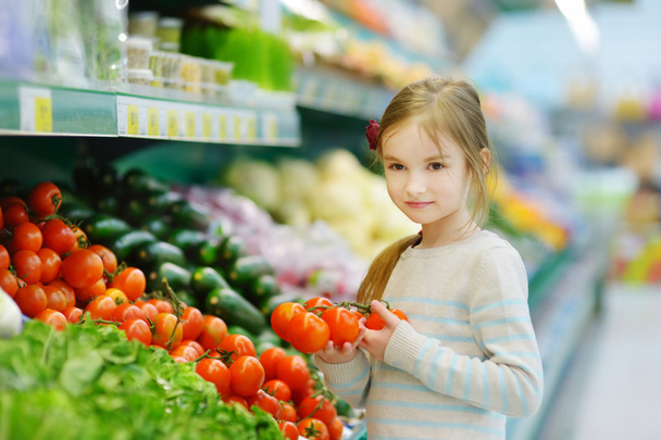 Little girl choosing tomatoes - 写真・画像