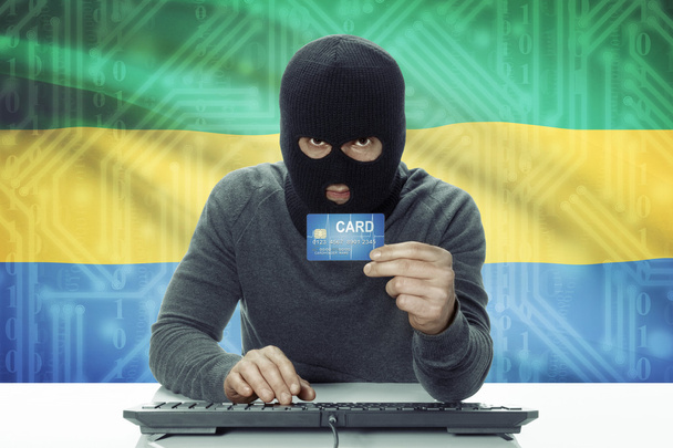 Hacker de piel oscura con bandera sobre fondo con tarjeta de crédito - Gabón - Foto, imagen