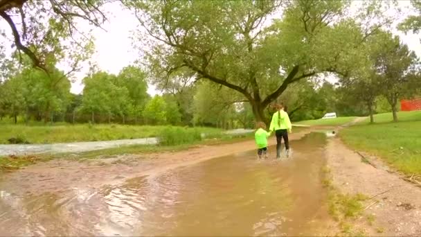 Δύο παιδιά, το περπάτημα σε λακκούβες στο πάρκο - Πλάνα, βίντεο