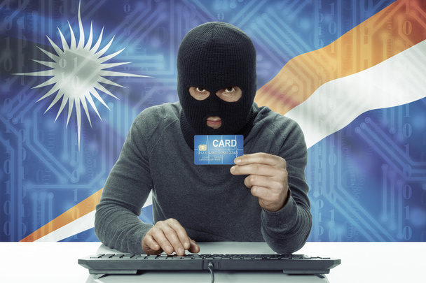 Dark-skinned hacker with flag on background holding credit card - Marshall Islands - Φωτογραφία, εικόνα