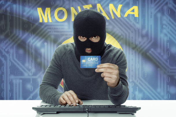 Dark-skinned hacker with USA states flag on background holding credit card - Montana - Foto, imagen