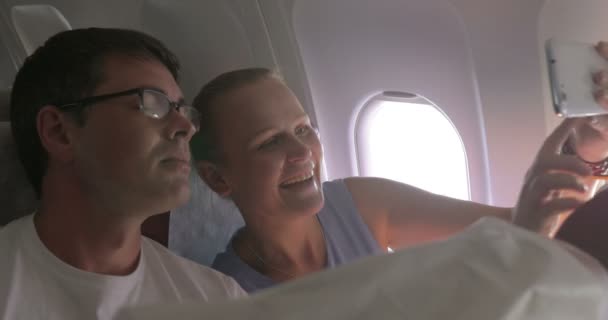 Νεαρό ζευγάρι κάνει selfie με το κινητό στο αεροπλάνο - Πλάνα, βίντεο