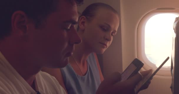 Young people using tablet PC and cell phone in plane - Felvétel, videó