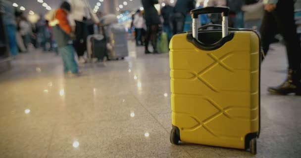 Maleta amarilla en el suelo en el aeropuerto lleno de gente
 - Metraje, vídeo