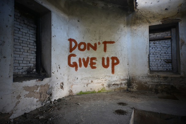 κείμενο μην εγκαταλείπετε την προσπάθεια στον παλιό βρώμικο τοίχο σε ένα εγκαταλελειμμένο ερειπωμένο σπίτι - Φωτογραφία, εικόνα