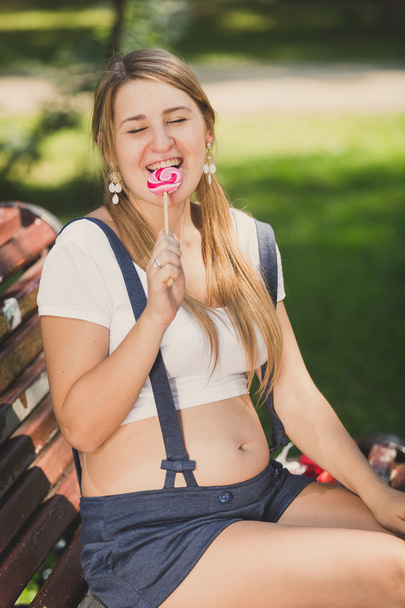 Toned portrait of pregnant woman licking lollipop at park - Fotografie, Obrázek
