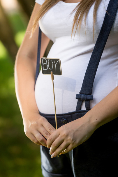 Closeup of pregnant woman holding blackboard with word "Boy" - Fotó, kép