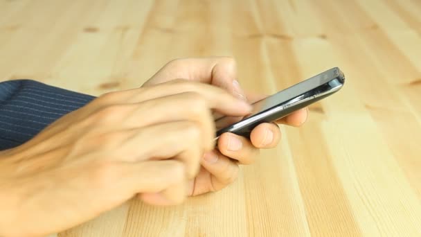 O empresário usa a corrediça do dedo e a tela de toque do telefone inteligente na mesa de madeira
 - Filmagem, Vídeo