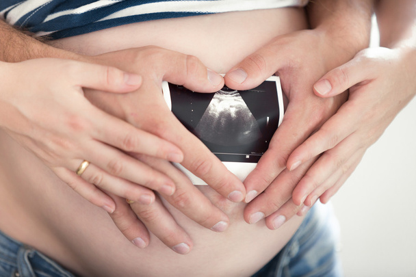 homem e mulher grávida segurando imagem de ultra-som no estômago
 - Foto, Imagem