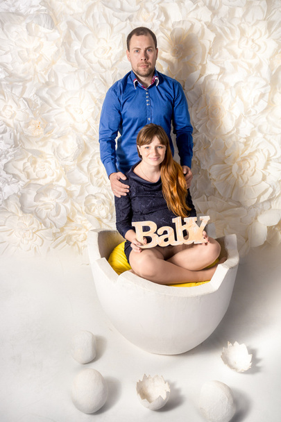 очікувані батьки позують на великій яєчній шкаралупі з декоративними яйцями
 - Фото, зображення