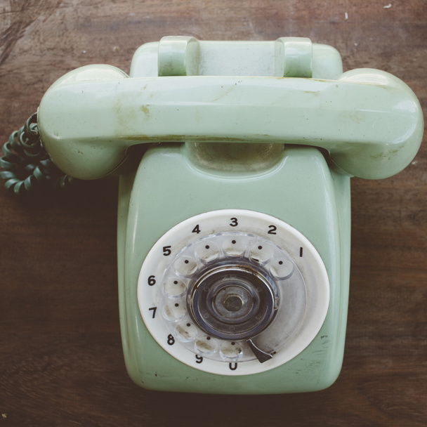 Green vintage telephone on brown wood desk background - Photo, Image