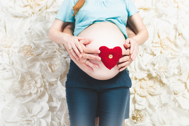 Gros plan des futurs parents tenant le foyer rouge sur le ventre
 - Photo, image