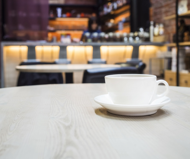 Kaffeetasse auf dem Tisch mit verschwommener Theke Bar Café Restaurant Hintergrund - Foto, Bild