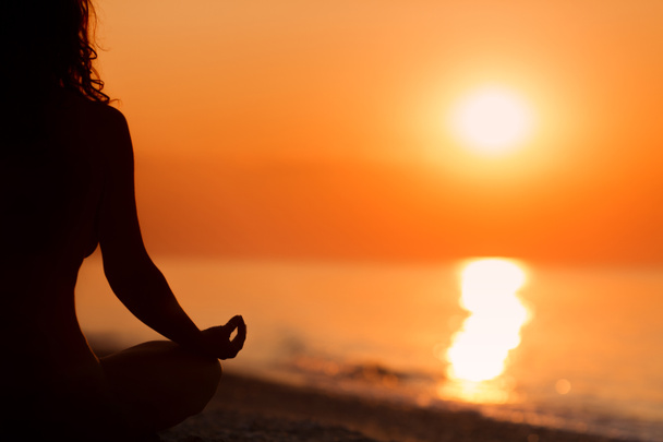 Silhouette della donna in posizione di meditazione loto yoga davanti a s
 - Foto, immagini