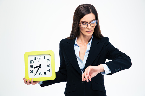 Businesswoman holding wall clock and looking on wristwatch - Zdjęcie, obraz