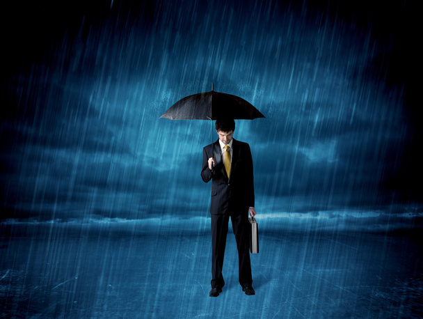 Geschäftsmann steht mit Regenschirm im Regen - Foto, Bild