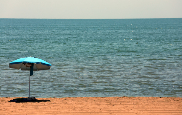 ізольована пляжна парасолька посеред пляжу
 - Фото, зображення