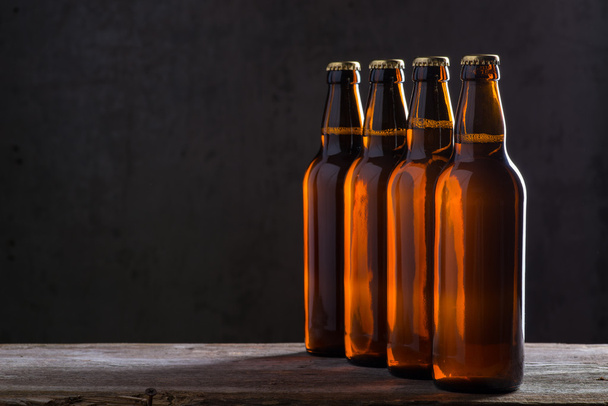 Freshly brewed beer bottles in a row over the grey concrete wall - Φωτογραφία, εικόνα