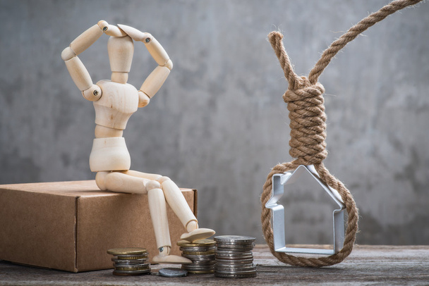 Small wooden dummy sitting with hangman's noose, house and coins - Photo, Image