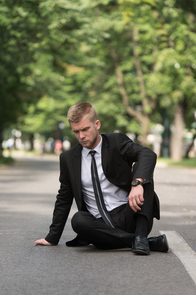 Empresario cansado sentado en asfalto al aire libre en el parque
 - Foto, Imagen