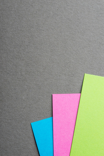 Голубой, зеленый и розовый лист бумаги на сером фоне
 - Фото, изображение