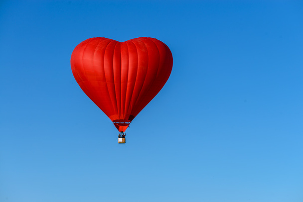 Red hot air balloon in the shape of a heart against the blue sky - Foto, Bild