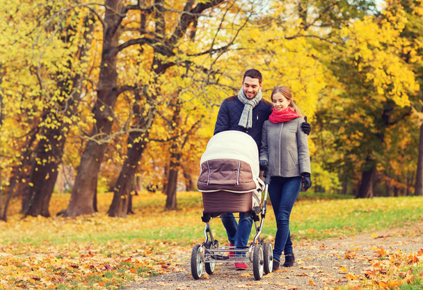 smiling couple with baby pram in autumn park - Foto, afbeelding