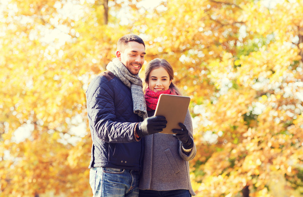 smiling couple with tablet pc in autumn park - Φωτογραφία, εικόνα