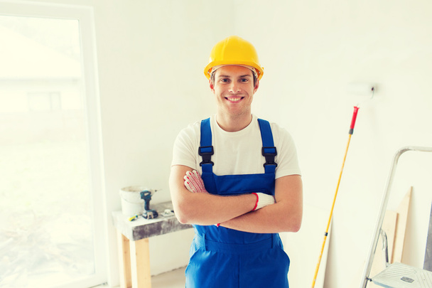 smiling young builder in hardhat  indoors - Zdjęcie, obraz