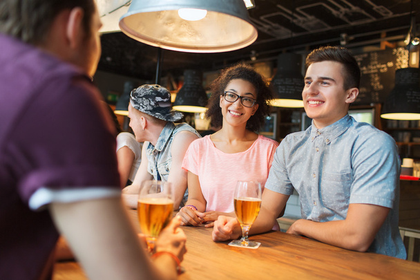 happy friends drinking beer and talking at bar - Valokuva, kuva