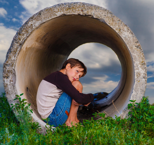 Triest tiener dakloze jongen zitten in de concrete pijp agoraphob - Foto, afbeelding