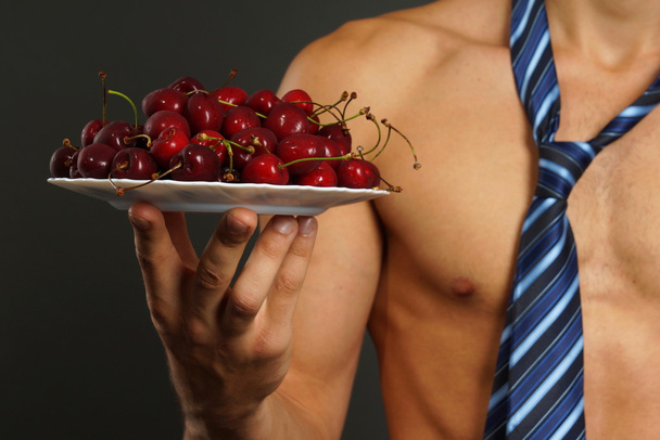 Young man shows you red fresh cherries - Zdjęcie, obraz