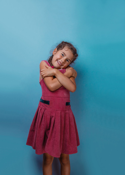 Δεκαετία Ευρωπαϊκής εμφάνιση κορίτσι Αγκαλιάζοντας τον εαυτό της σε ένα μπλε έκφραση - Φωτογραφία, εικόνα