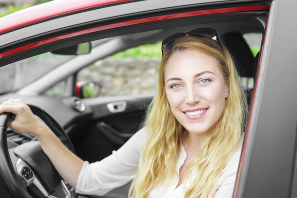 Χαμογελαστά νεαρή όμορφη ξανθιά γυναίκα στο αυτοκίνητο, γκρο πλαν. - Φωτογραφία, εικόνα