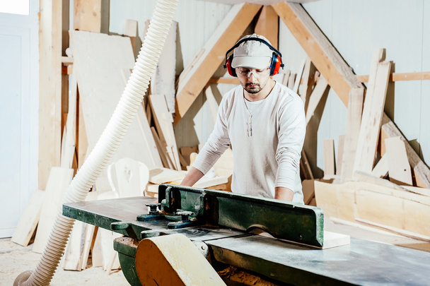 Carpenter working cutting some boards, he is wearing safety glasses and hearing protection - 写真・画像