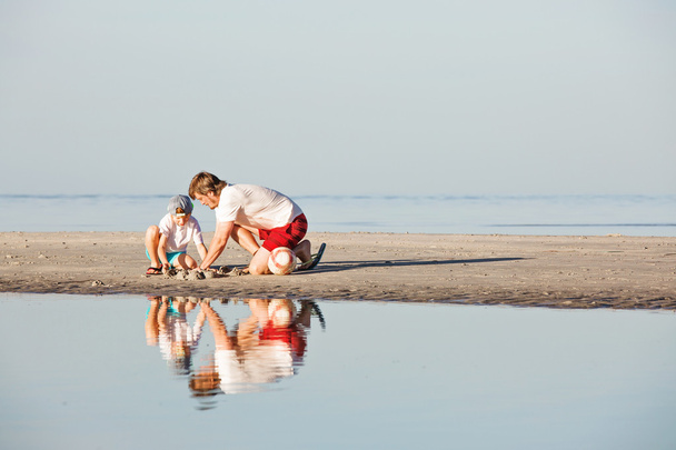Mutlu baba ve oğul sahilde günbatımı ışığı iyi vakit geçiriyor - Fotoğraf, Görsel