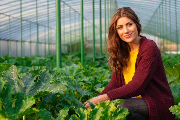 Beautiful young woman gardening and smiling at camera - Фото, изображение