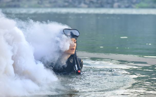 Mujer buceadora en agua envuelta en humo
 - Foto, imagen