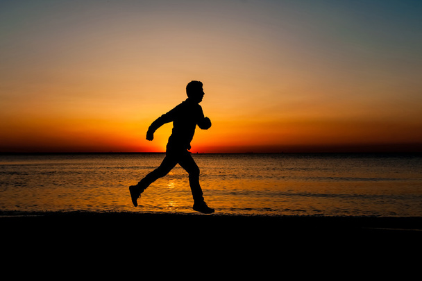 Silhouette of running man on the beach at sunrise - Photo, Image