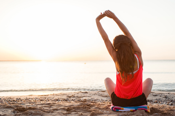 Silhouette junge Frau übt Yoga am Strand bei Sonnenaufgang. - Foto, Bild