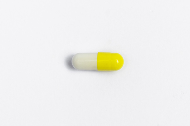 white pill isolated. Single white, yellow capsule closeup. pill macro - Zdjęcie, obraz