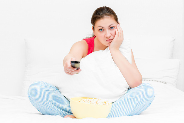 girl in pajamas with remote control TV dissatisfied - Foto, Bild