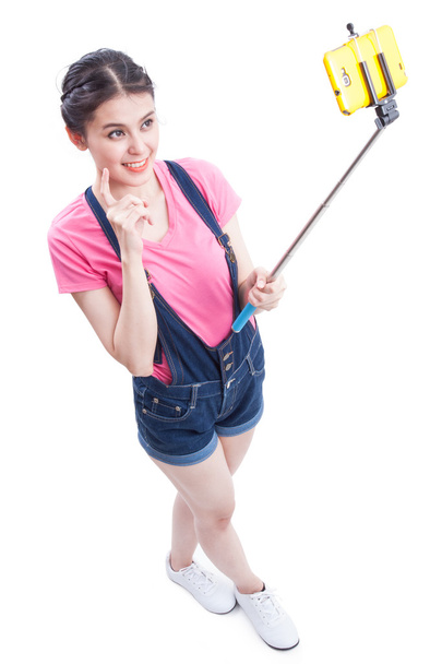 Happy woman taking picture with smartphone selfie stick - Фото, изображение