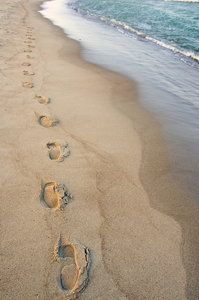 kenar boşluğuna ulaşan dalgaların ayak izlerini. romantik bir yürüyüş. - Fotoğraf, Görsel