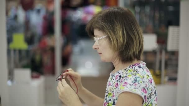Senior woman chooses new glasses - Séquence, vidéo