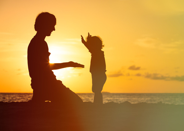 Vater und kleine Tochter spielen Silhouetten bei Sonnenuntergang - Foto, Bild