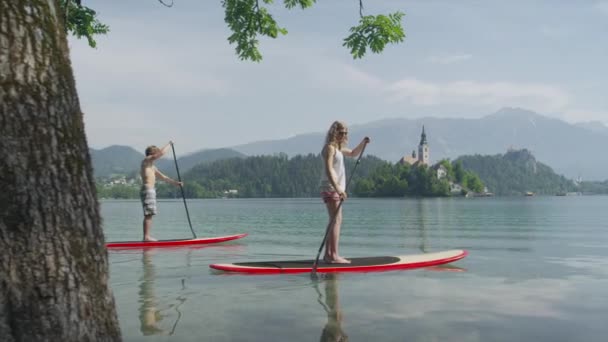 SLOW MOTION: Boyfriend taking girlfriend SUPing on beautiful lake in summer - Footage, Video