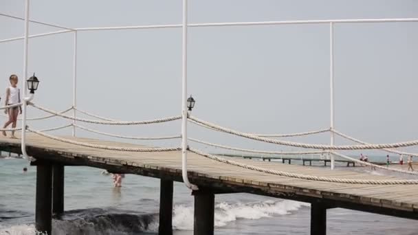 Child walking on a wooden pier near the sea - Кадри, відео